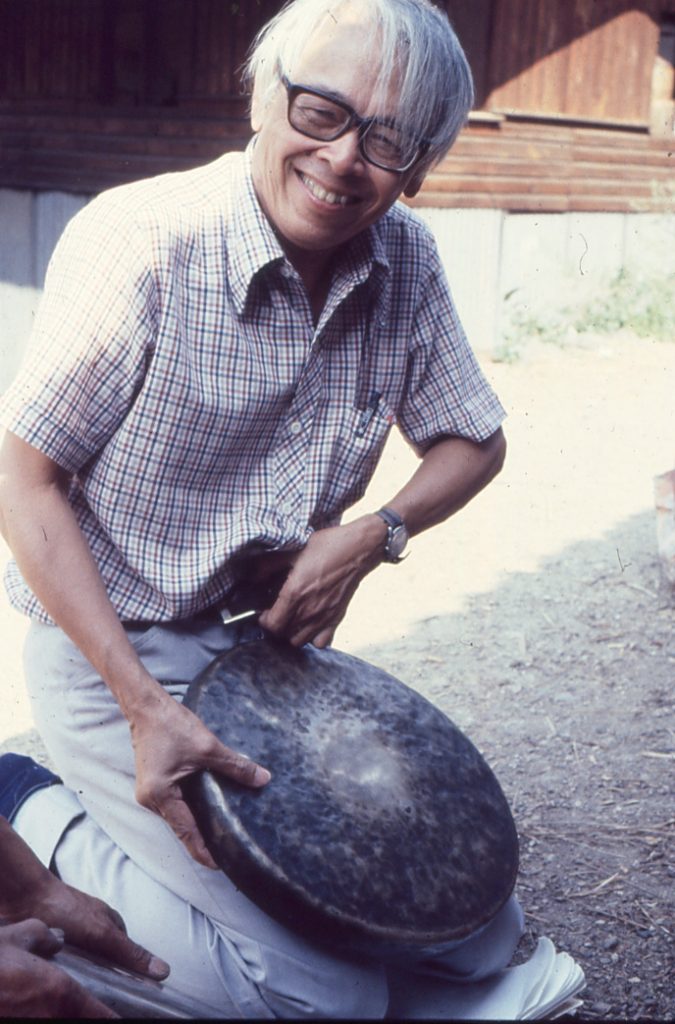 Dr Jose Maceda holding a flat gong during a trip in Bontok